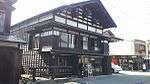 A two level wooden house with partially white walls.