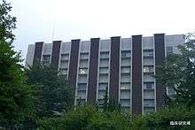 Rectangular grey-and-black building, surrounded by trees