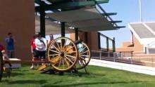 A woman yells "Fire in the hole" before firing an empty round in a cannon towards an empty stadium