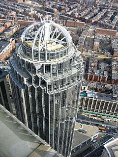 Angled aerial view of an all-glass building capped with a white, open-air dome