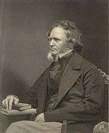 A stately-looking gentleman in a dark suit, sitting with a book