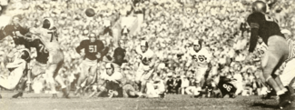 A beige image of a football being thrown between two players in black jerseys