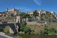 City with churches and other large structures on a hillside near a river.