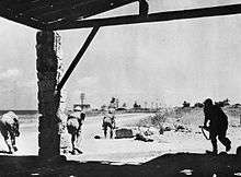 Soldiers advance under fire along a desert road towards a wireless station