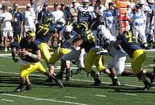 a quarterback rolls out while his offensive line blocks