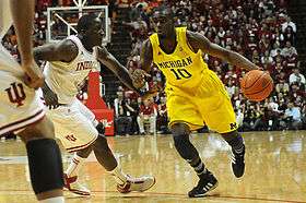 Player dribbling, guarded by two players in white uniforms