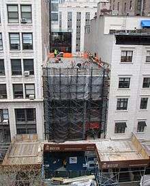 The first four floors of a narrow building under construction are situated between two other, taller buildings.