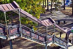 A staircase from the sidewalk to the elevated station house. It has decorative railings with peeling black paint.