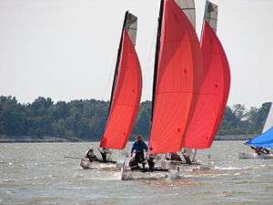 Three catamarans with red sails.