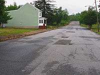 and an unbuttressed side of a similar house on an otherwise deserted street with a single street light on a utility pole