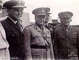 Half portrait of seven men in military uniforms with peaked caps, three featured in foreground