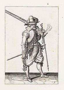 A pen and ink drawing of a soldier with a large musket over his shoulder.  He wears elaborate 16th-century clothing including puffy knee breeches and a wide brimmed, tall hat with a plume.