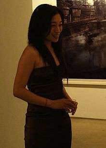 A long-haired East Asian woman in a black dress