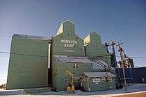 Two green elevators in winter, against a blue sky