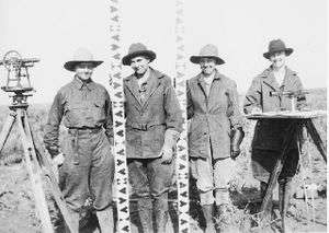  Four women pose with a theodolite, a plane table and two levelling staves.