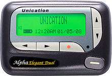 A gray boxlike object with rounded corners and buttons with arrowheads, circles and a dash. Text in the lower left hand corner reads "Alpha Elegant Dual". In the center is a luminous green liquid crystal display with "Unication" in large letters on top, a speaker and battery icon at the lower left and "12:20AM 01/05/08" in smaller text across the bottom