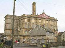 Four storey building with chimney behind gates and walls.