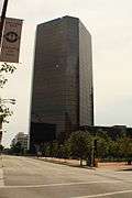 A glassy black tower stands beyond some small trees.