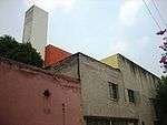 House consisting of differently colored blocks: grey, pink, red, white.