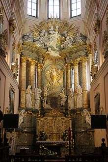 A gilded altar with six marvel columns and several sculptures in the background