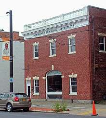 A two-story brick building, similar to but smaller than the house, with an arched entry in the middle