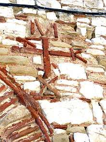 Photo of a monogram formed by red bricks set in a wall