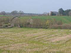 A few buildings scattered among fields and trees.