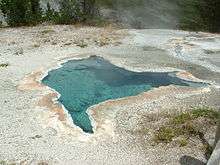 Irregular-shaped pool of crystal clear water in ashen rocks.