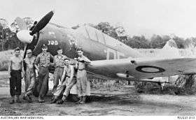 Six men stand around the nose of a radial-engined fighter plan