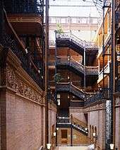 A photograph of a building interior showing stairs climbing up five storeys to the final floor where we can see the glass roof.