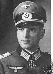 A man wearing a peaked cap and military uniform with an Iron Cross displayed at the front of his uniform collar.