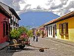 Street with colorful single-storied houses with window grills.