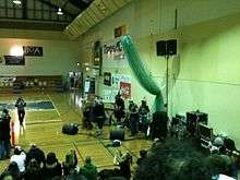 A band playing guitar and singing in a gymnasium