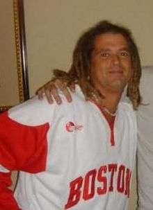 A man wearing dreadlock and red and white shirt.