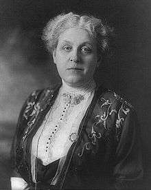 Middle-aged woman with short hair, in white blouse and dark jacket