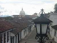 Low old houses and a church with a large white cupola in the distance.