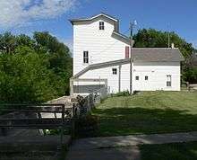 Two- or three-story wood building beside concrete sluice