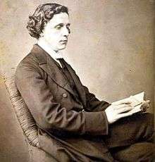 Photographic portrait of Charles Lutwidge Dodgson (Lewis Carroll), seated and holding a book