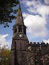 The west end of a Gothic church showing its stepple with a square lower stage, octagonal belfry stage surmounted by a spire