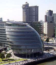 Nine-story rounded glass building beside river.