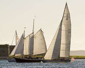 Photograph of Columbia on the right overtaking two other yachts.