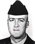 Head of a white man wearing a garrison cap and a dark military jacket over a light-colored shirt.