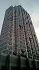  DKLB BKLN, a high-rise clad in stone and blue glass with curved corners, viewed from street level