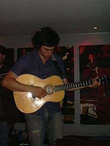 Young man playing an acoustic guitar with a focused expression