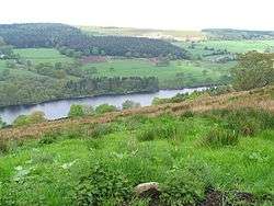 View across a partially wooded valley containing a reservoir