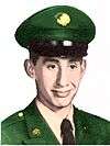 Head of a young smiling Hispanic man wearing a green military uniform and peaked cap, with an American flag in the background.