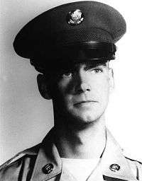 A black and white head shot of Shea in his military dress uniform with hat.