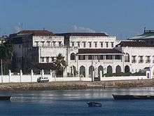 A distant view of a very large and luxurious building near a wide river.