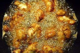 Battered chicken legs in bubbling oil.