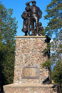 Photograph of a memorial at the Donner Camp, a set of bronze figures, woman, man, and child, atop a tall stone plinth.